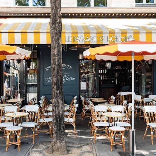 yellow striped awning café with wicker chairs and large street tree., le passage saint honoré, paris