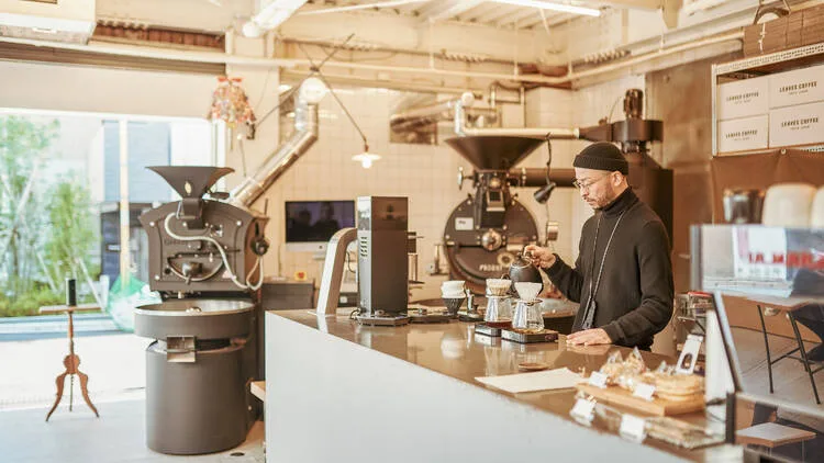 coffee roastery with barista at counter, industrial roasting equipment overhead., leaves coffee roasters, tokyo