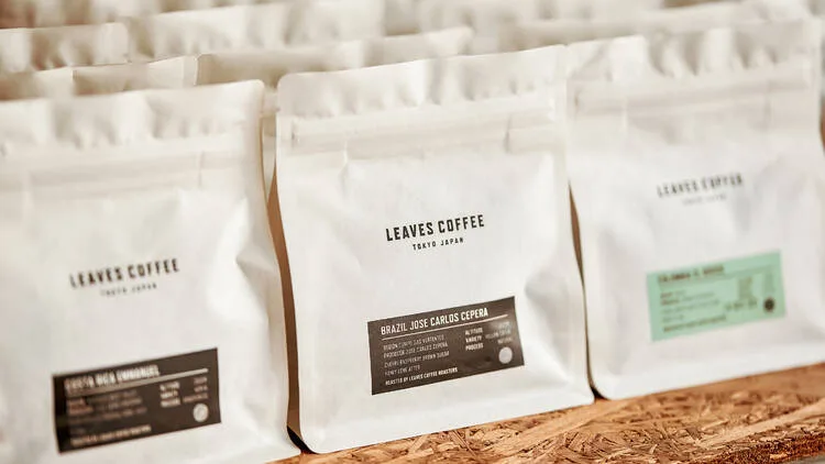 three white leaves coffee bags arranged on cork surface, specialty coffee packaging., leaves coffee roasters, tokyo