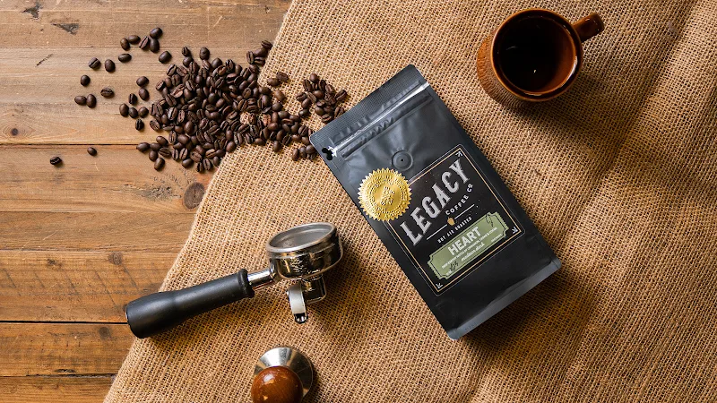 legacy coffee beans, grinder, brewed cup, and burlap cloth arranged on wooden surface., legacy coffee co., columbia