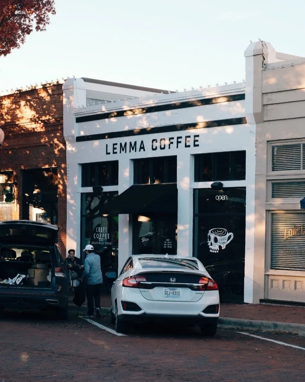 white storefront coffee shop with black striped awning and skull logo design., lemma coffee co, dallas