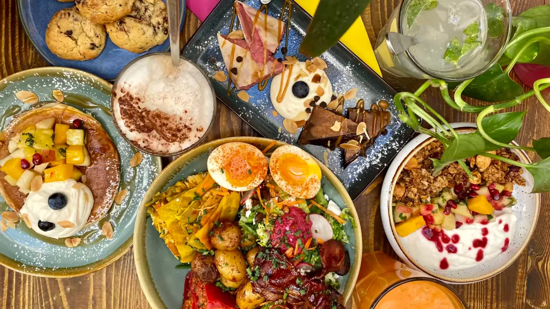 colorful brunch spread with eggs, toast, salads, desserts, and beverages on wooden table., les bariolés de maud paris 11, par
