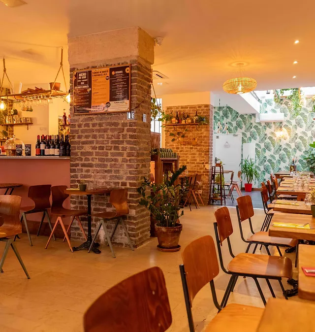 warm-lit modern café with brick pillars, red chairs, and potted plants., les bariolés de maud paris 11, paris