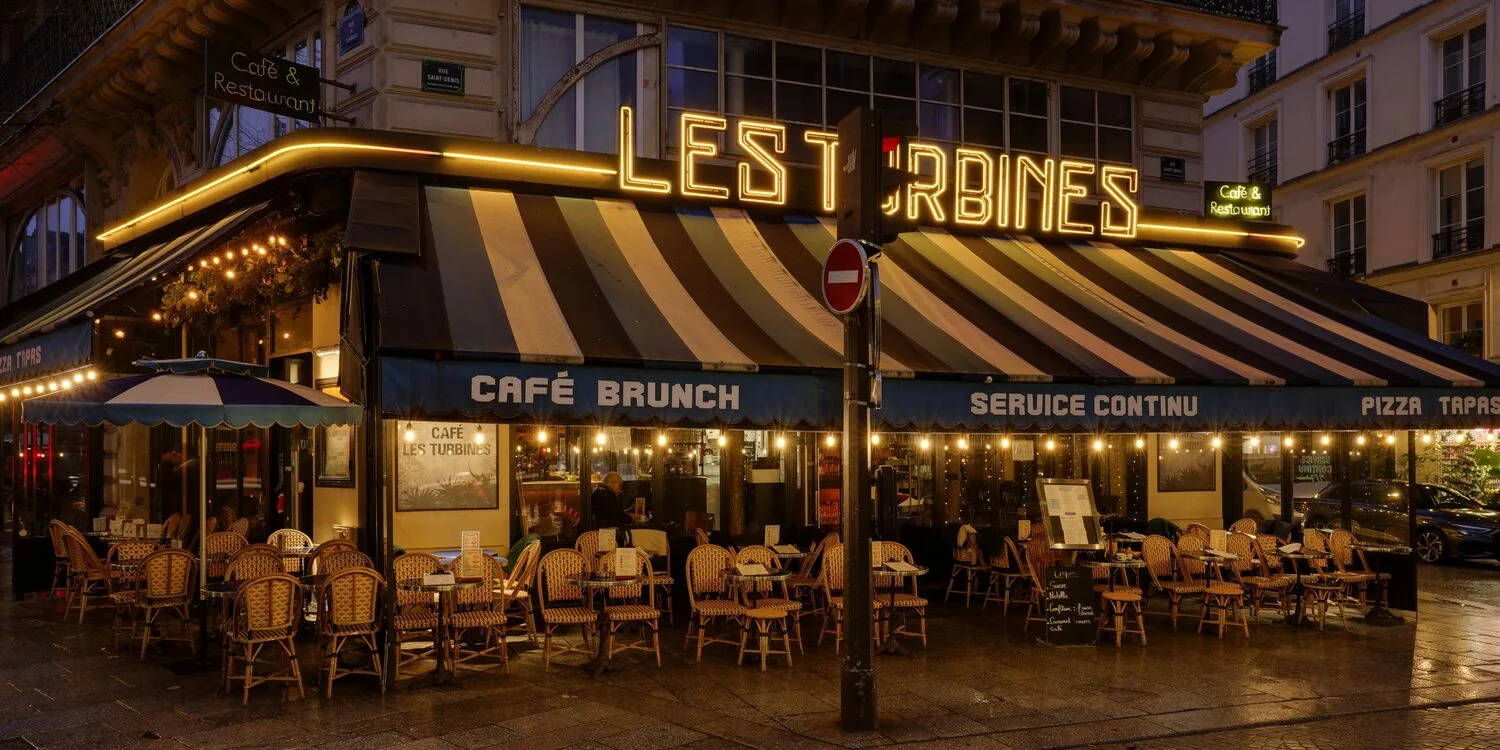 parisian café with glowing neon sign, striped awning, wicker chairs, evening ambiance., les turbines, paris