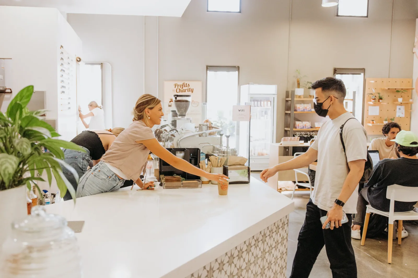 bright café interior with staff and customers interacting at white counter., lion and lamb coffee roasters, costa mesa
