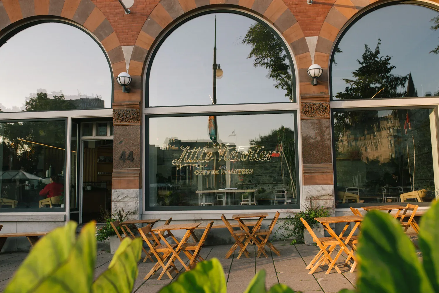brick storefront with arched windows, wooden chairs, and coffee shop signage., little victories coffee roasters - glebe, otta