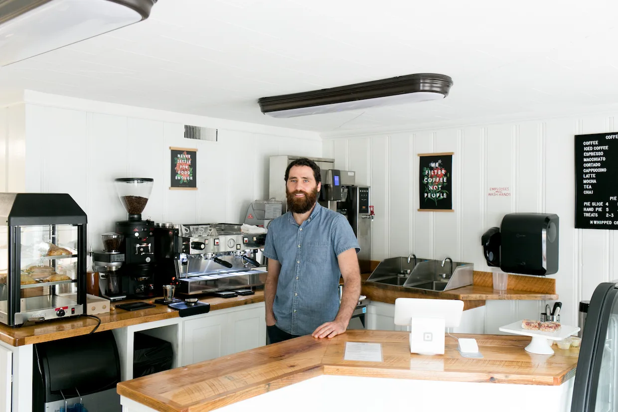man standing in modern coffee shop with espresso machines and wooden counters., lone light coffee, charlottesville