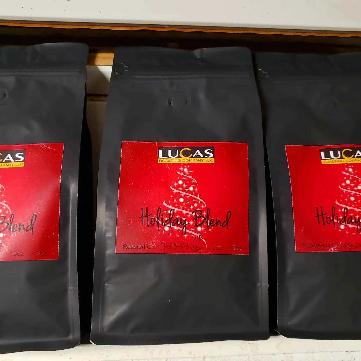 black coffee bags with red lucas roasting company holiday blend labels on shelf., lucas roasting company, llc, wolfeboro