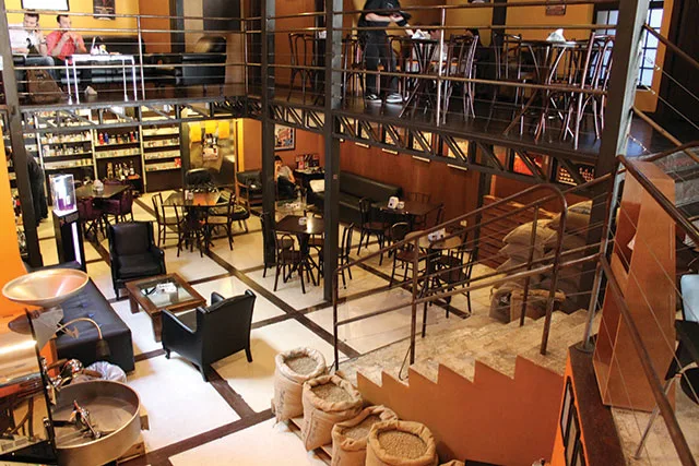 multi-level café interior with seating areas, tables, chairs, and warm lighting throughout., lucca cafés especiais, curitiba