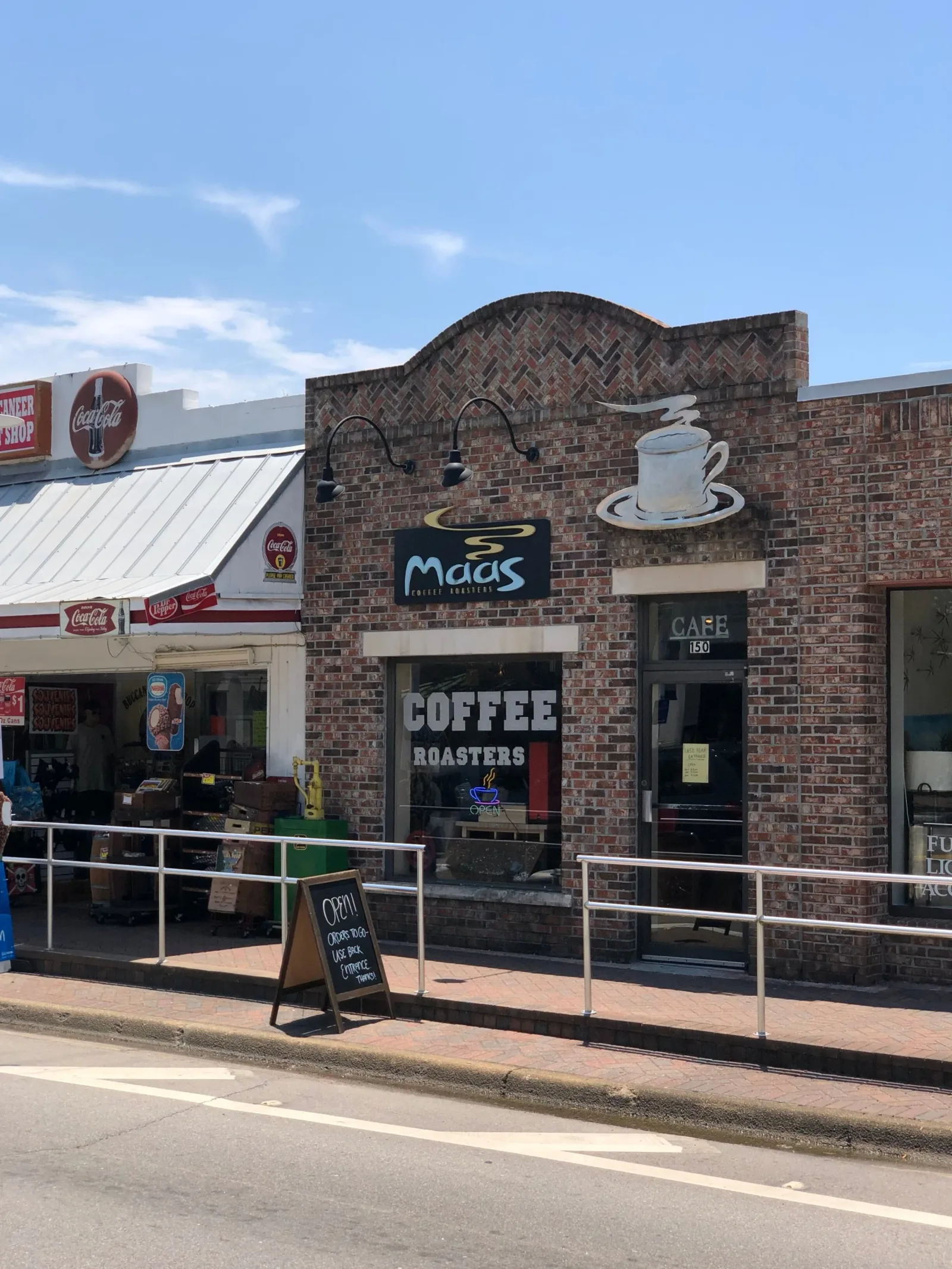 brick coffee shop with vintage signage and metal railings on sidewalk., maas coffee roasters, fort walton beach