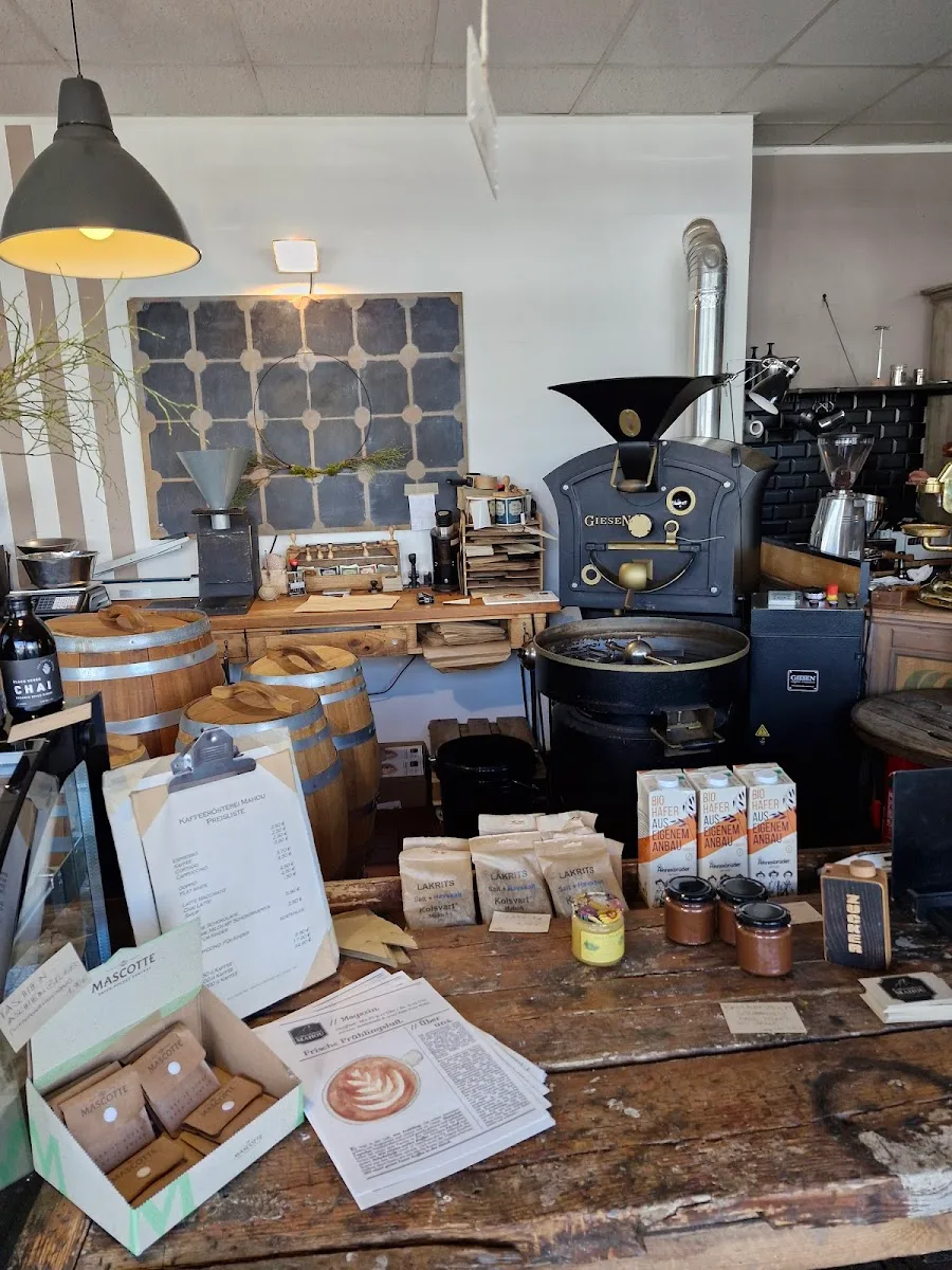 specialty coffee roastery display with equipment, packaged beans, and wooden barrels., mahou-kaffeerösterei, cologne