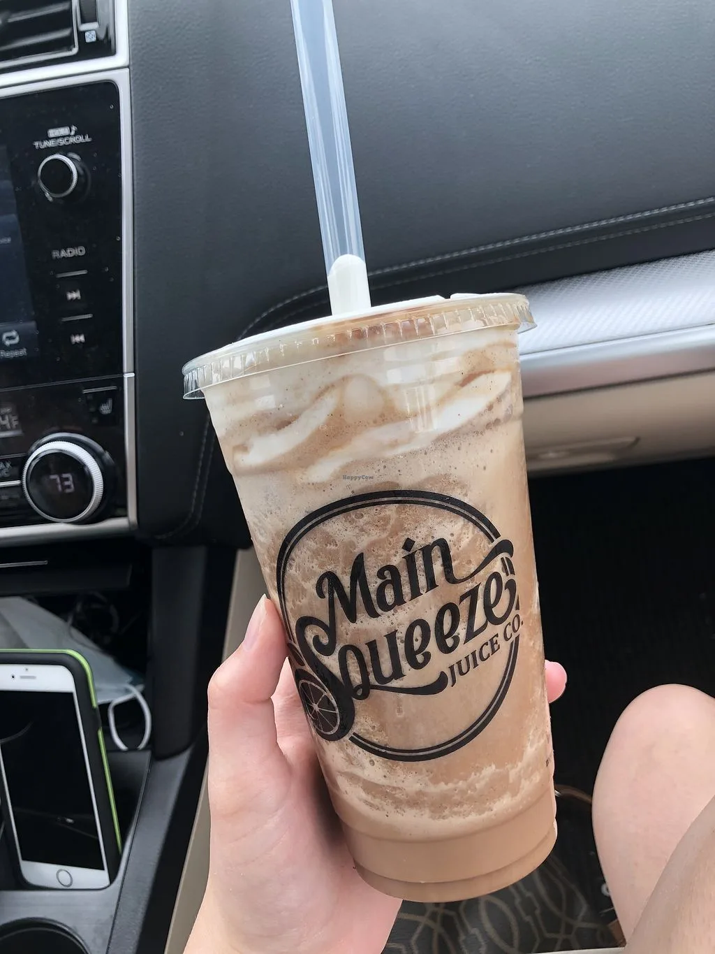 hand holding iced beverage from main squeeze juice company in car interior., main squeeze juice co., shreveport