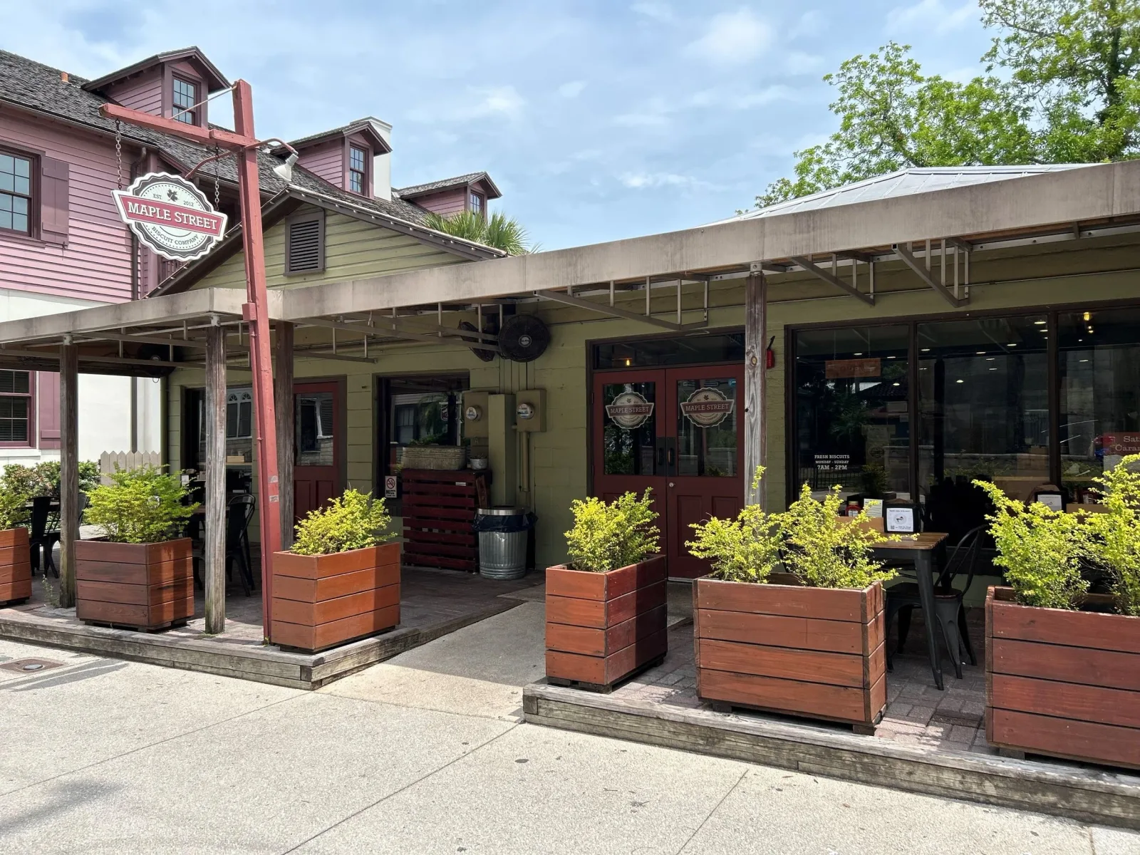 maple street storefront with covered patio, planters, and red doors., maple street biscuit company, saint augustine