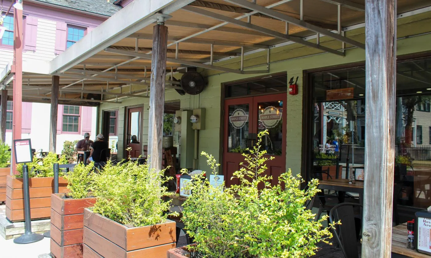 outdoor café patio with plants, rustic wooden beams, and red door entrance., maple street biscuit company, saint augustine