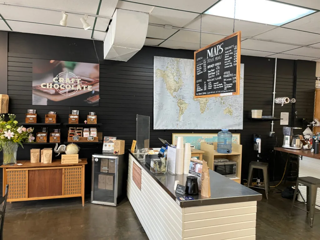 modern coffee shop interior with counter, world map, chocolate display, and menu board., maps coffee & chocolate, lenexa