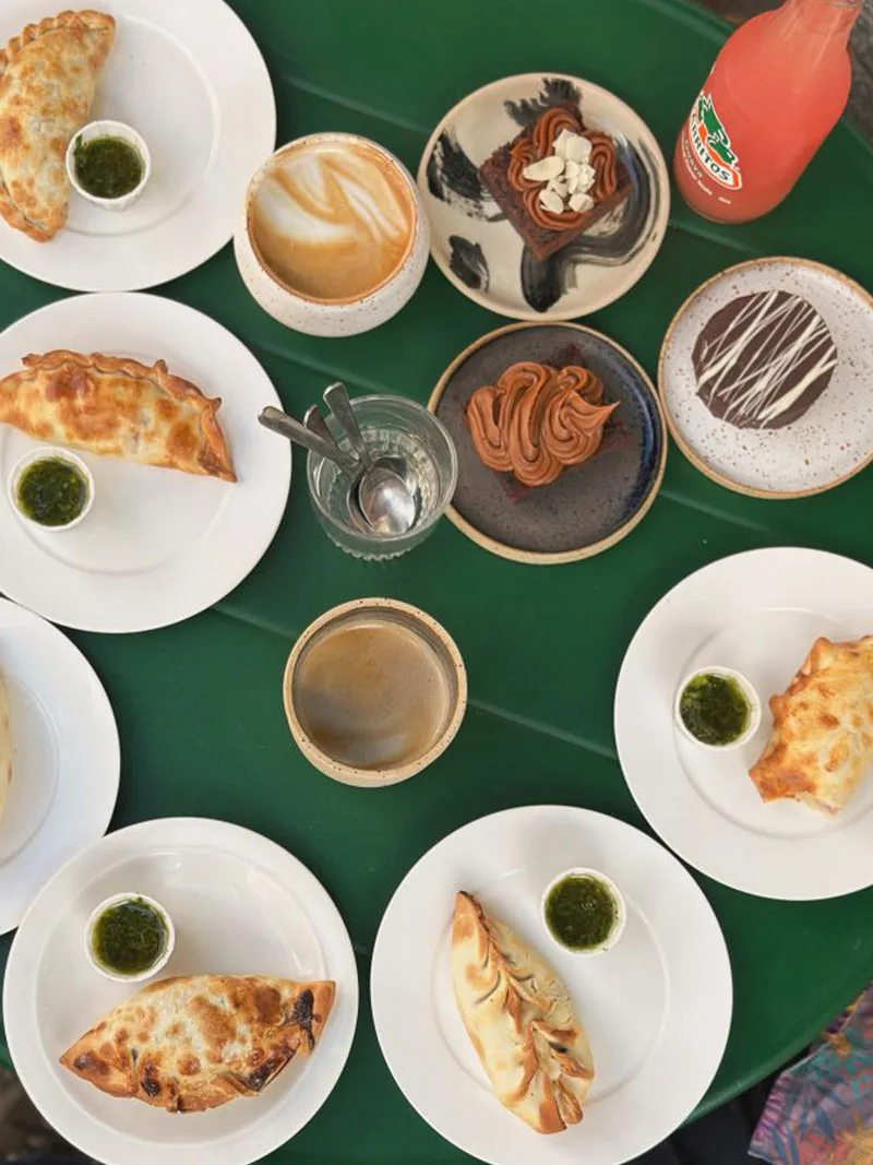 overhead view of argentine empanadas, pastries, and desserts on green table., mariki, gothenburg