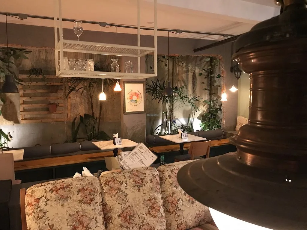 cozy restaurant interior with plants, wooden booths, pendant lights, and natural decor., marilda café, brasília