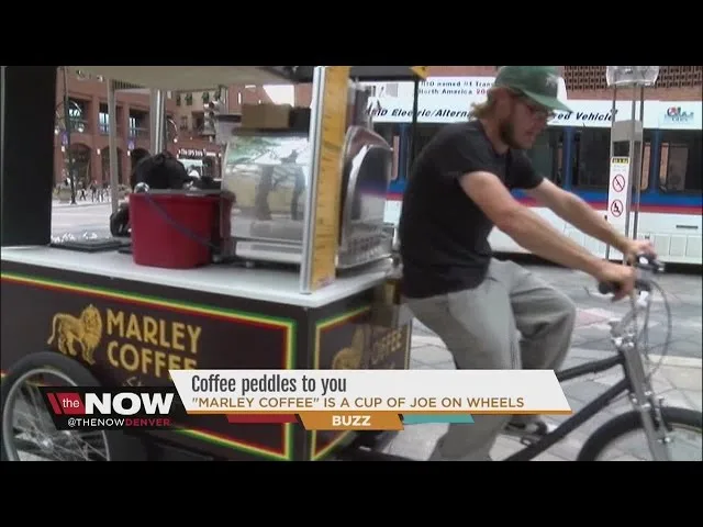 man pedals coffee cart through urban street serving beverages to customers., marley coffee, denver