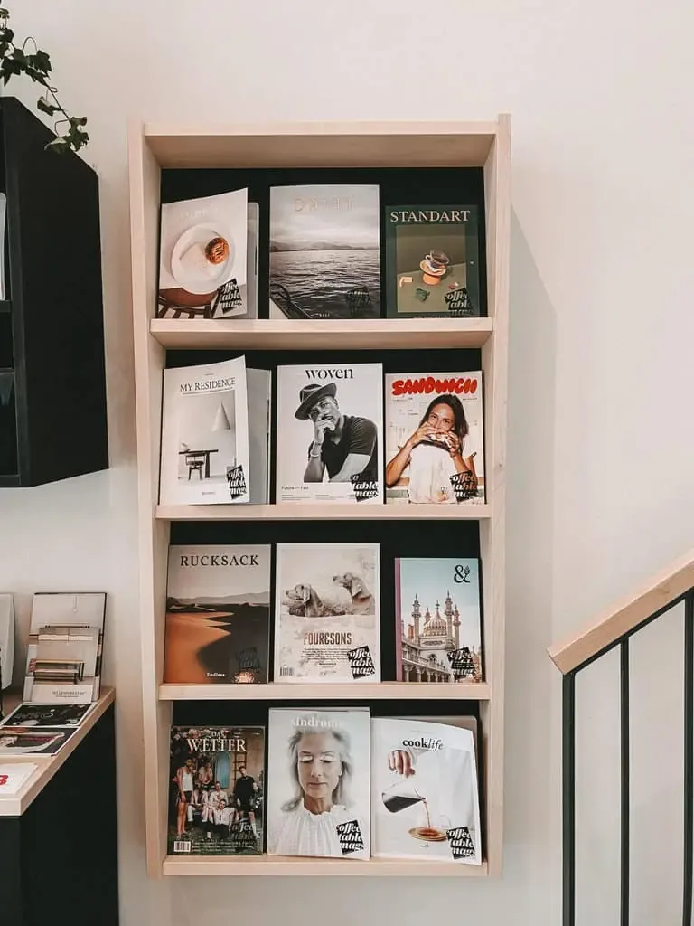 wooden wall-mounted shelving displaying magazines and publications with black backgrounds., marshall street coffee, hamburg