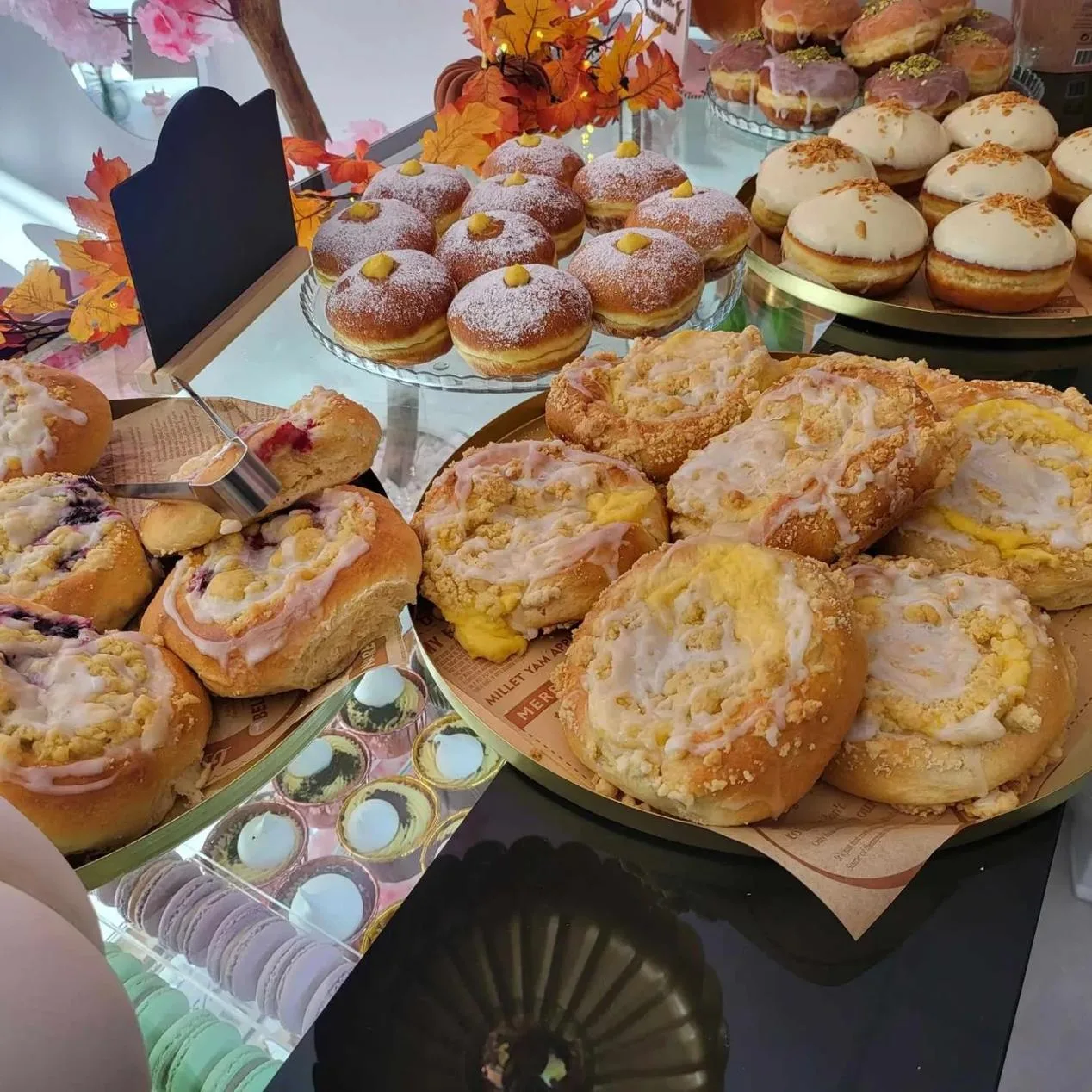 autumn-themed bakery display with pastries, donuts, macarons, and decorative fall leaves., martha's fancy kaker atelier, berg