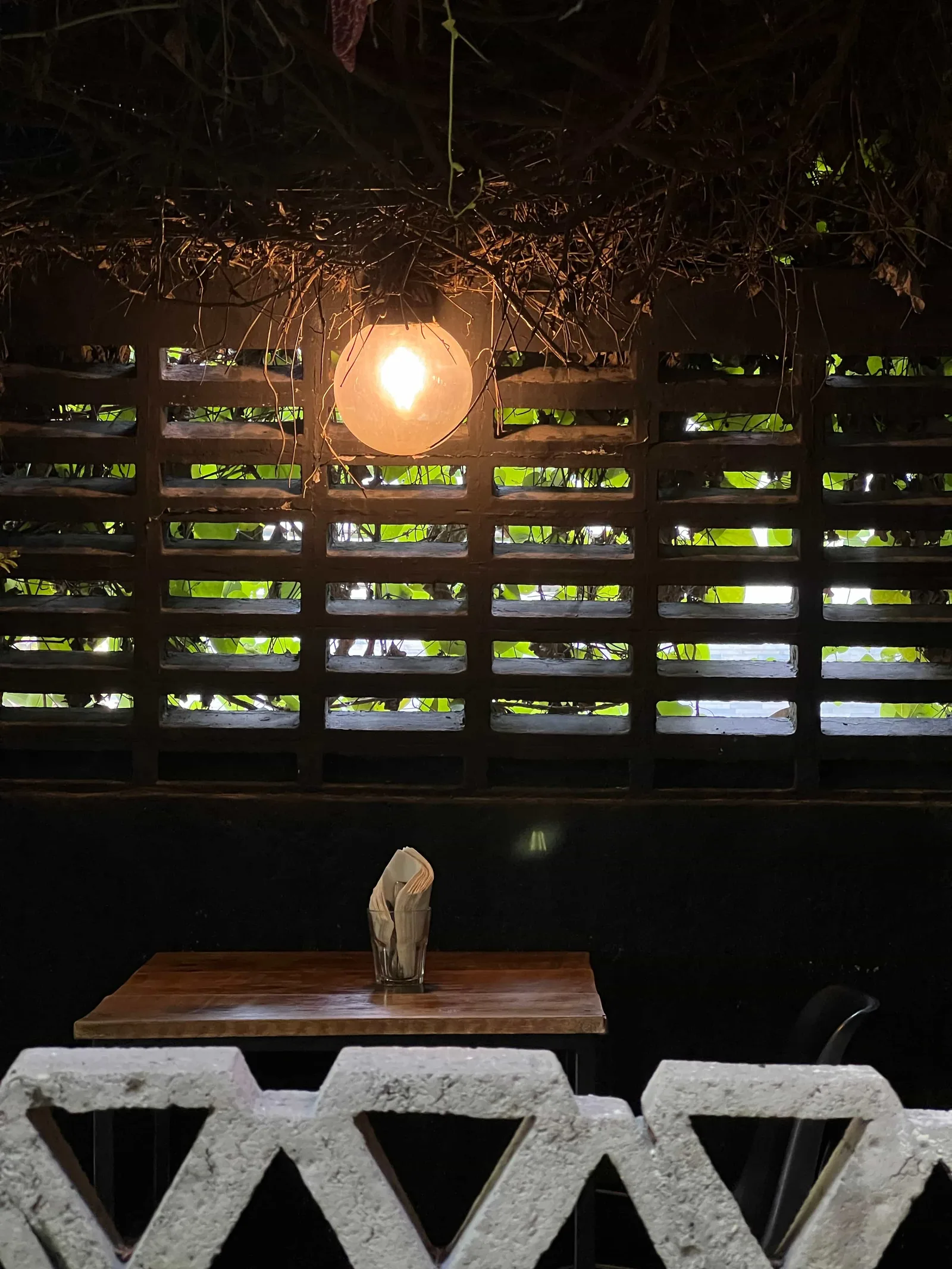 wooden table with napkin holder under warm hanging lamp and wooden lattice wall., matraz tostador, guadalajara
