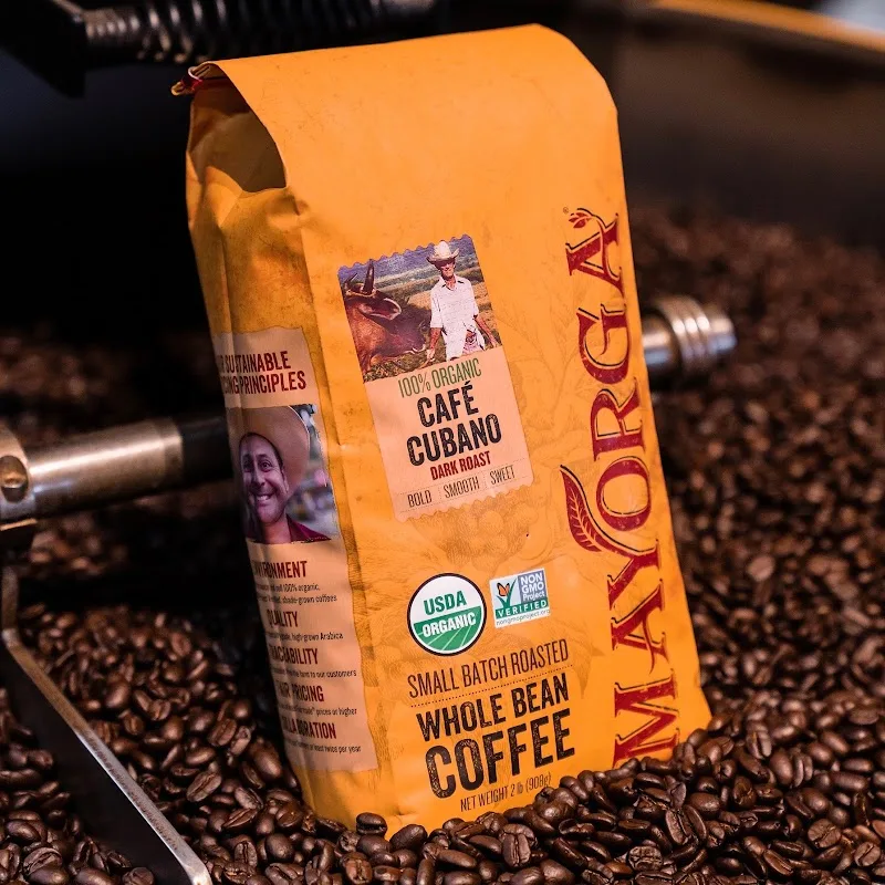 orange bag of organic café cubano whole bean coffee surrounded by roasted beans., mayorga coffee, rockville