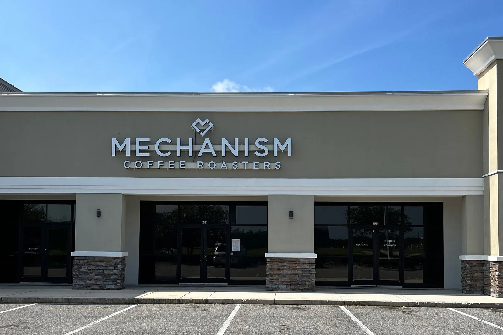 modern coffee roastery storefront with large windows and stone accents., mechanism coffee roasters, jacksonville