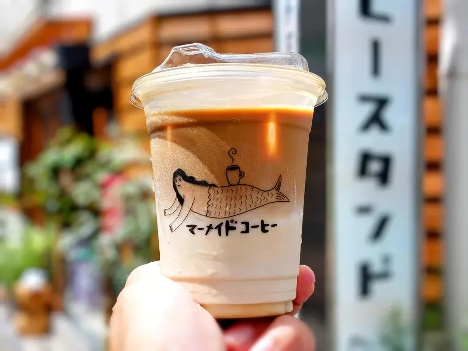 hand holding iced coffee with mermaid illustration and japanese text on cup., mermaid coffee roasters, sapporo