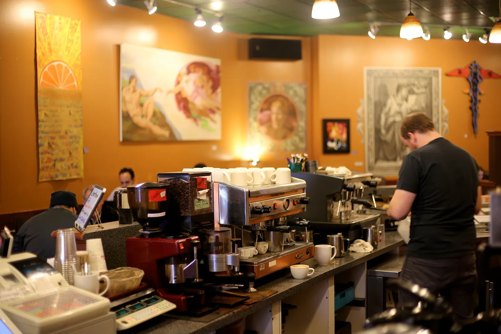 coffee shop interior with espresso machines, baristas working, warm orange walls, artwork displayed., michelangelo's coffee h