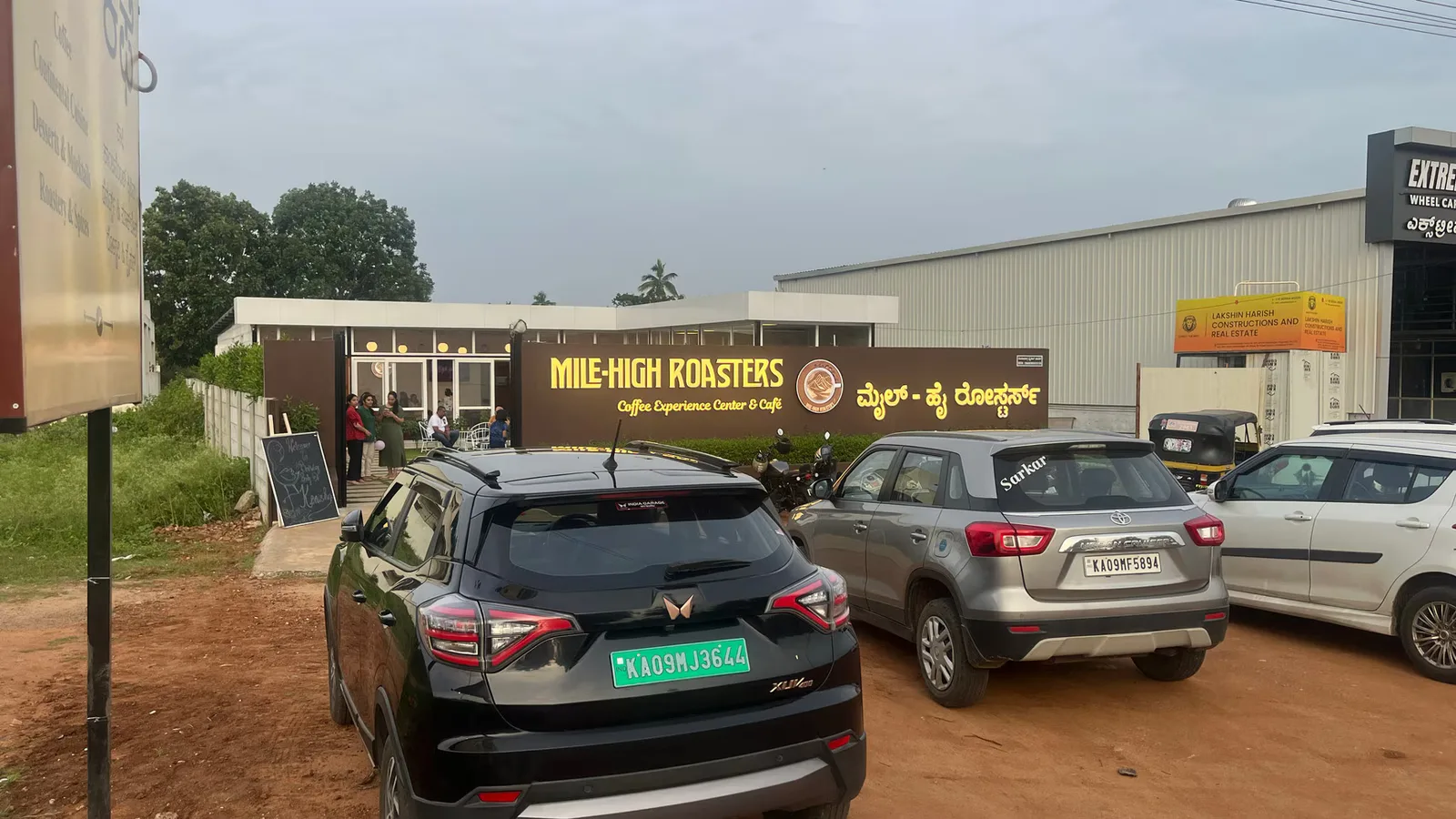 mile-high roasters coffee shop with parked cars and customers outside entrance., mile high roasters, mysuru