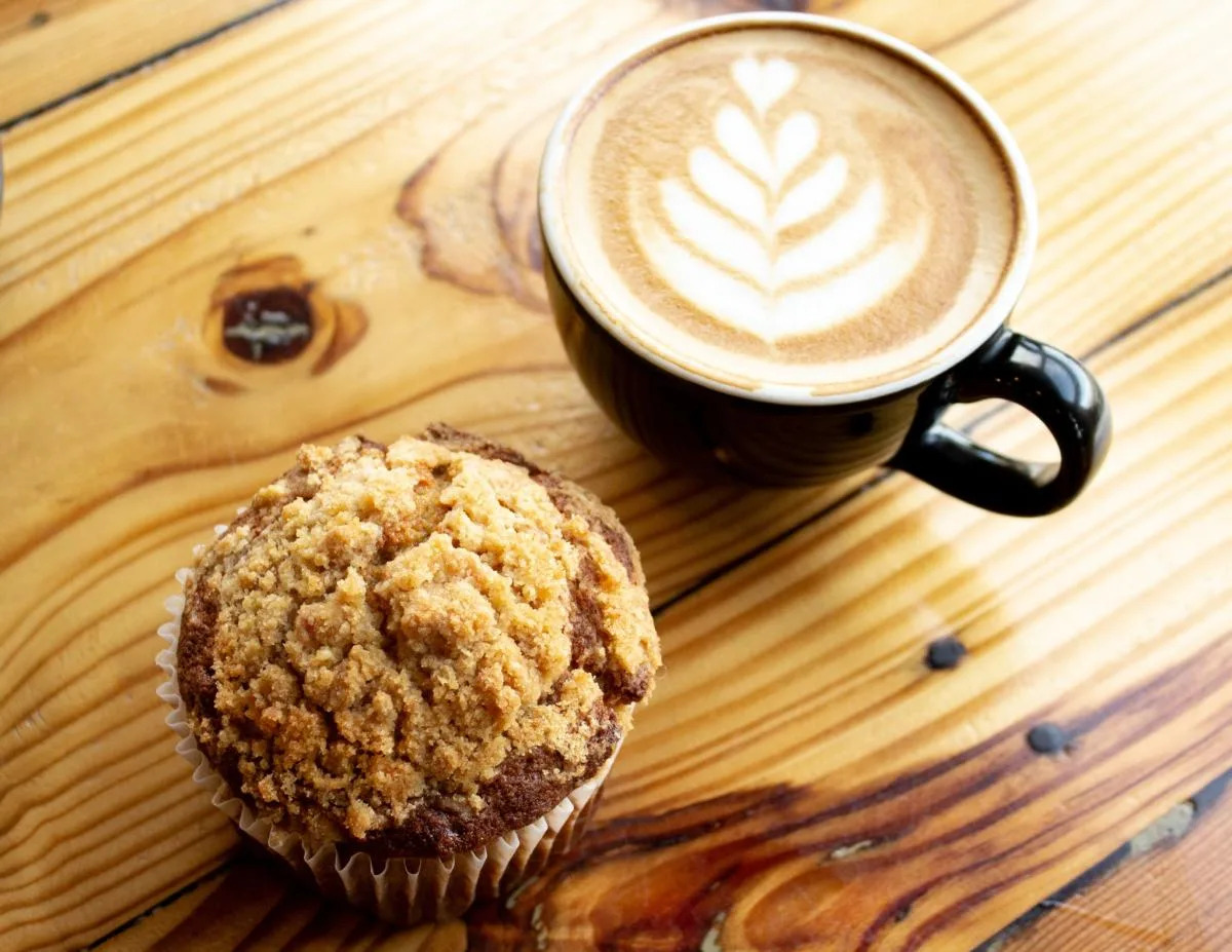muffin with crumb topping beside cappuccino with latte art on wooden table., miller's smokehouse, temple