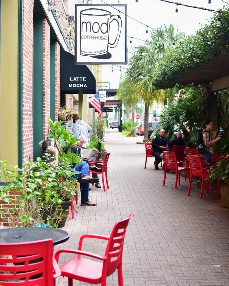 outdoor coffee shop patio with red chairs and hanging string lights overhead., mod coffeehouse, galveston