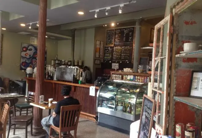 cozy cafe interior with counter, pastry display case, and seated customer., mod coffeehouse, galveston