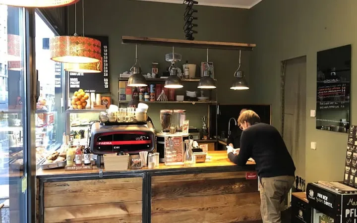 coffee shop interior with barista, espresso machine, pendant lights, and wooden counter., mod rockers roastery & bagels, berl