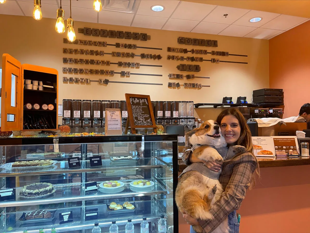 woman holding dog in espresso café with pastry display cases and menu board., momentto coffee roasters, chandler