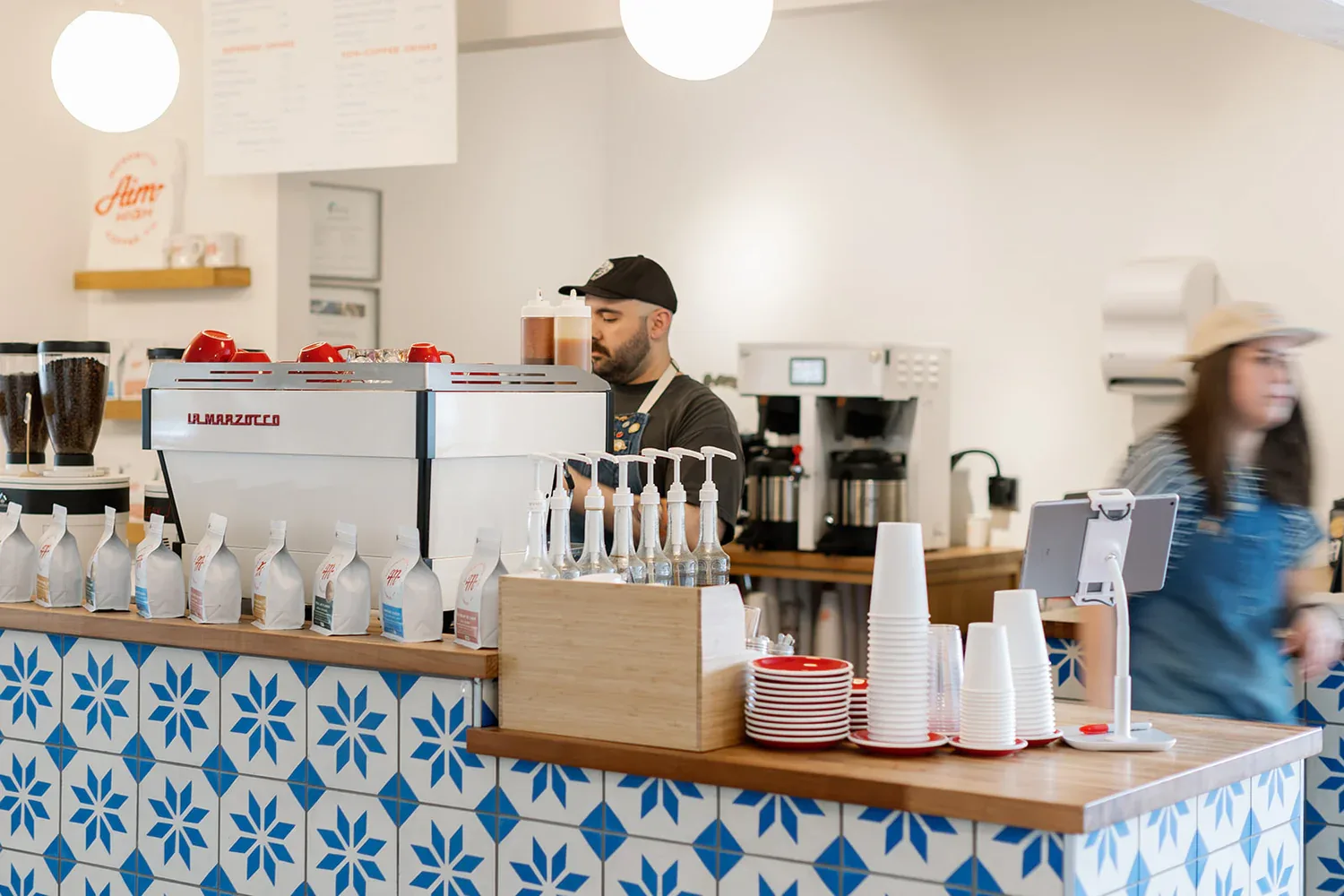 coffee shop counter with barista, espresso machine, cups, and product display., monomyth coffee, lubbock