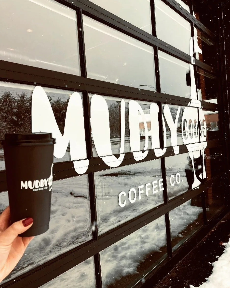 person holding black muddy coffee co. cup outside snowy storefront window., muddy goose coffee co., dayton