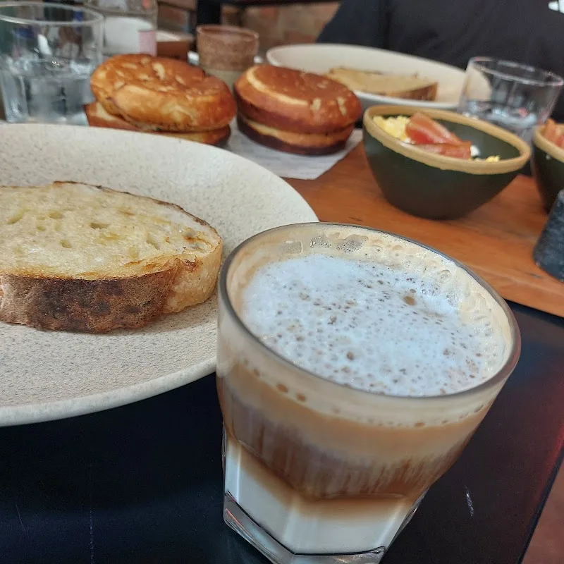 toasted bread, pastries, and layered coffee drink on wooden table., mug.sp - casarão barão de tatuí, são paulo