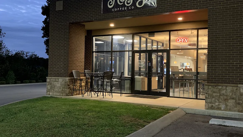coffee shop storefront at dusk with outdoor seating and illuminated interior signage., mugsy's coffee co, clarksville