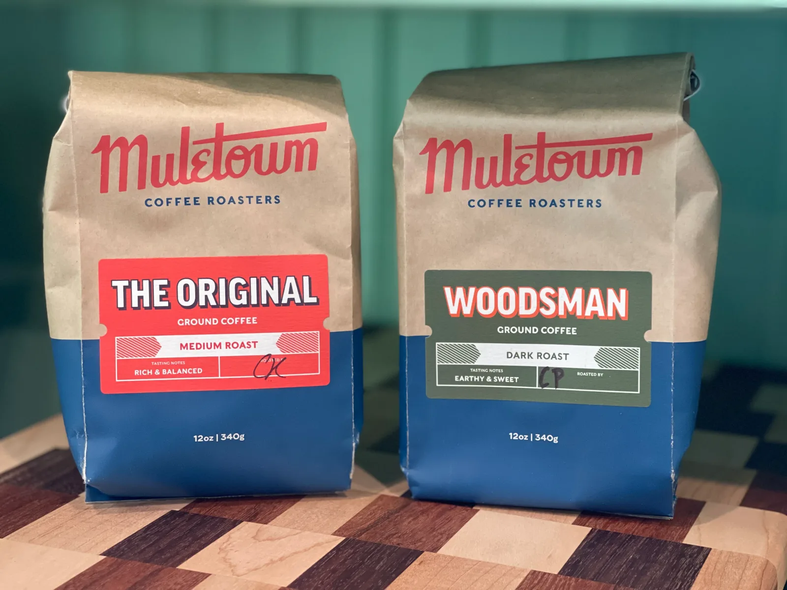 two mulstown coffee roasters bags on checkered wooden surface against teal background., muletown roasted coffee, tennessee