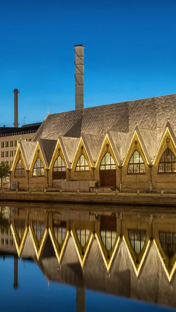 historic brick building with distinctive pointed arch windows reflected in canal water., musikens hus, gothenburg