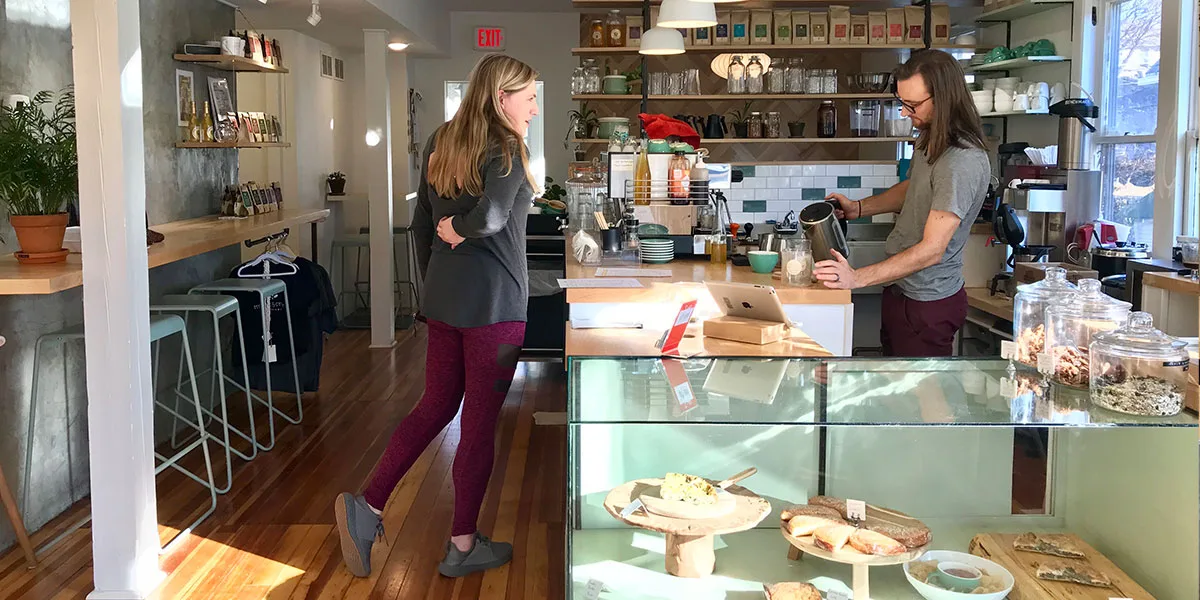 two women converse in a modern café with display cases and shelving., myrtle and cypress, omaha