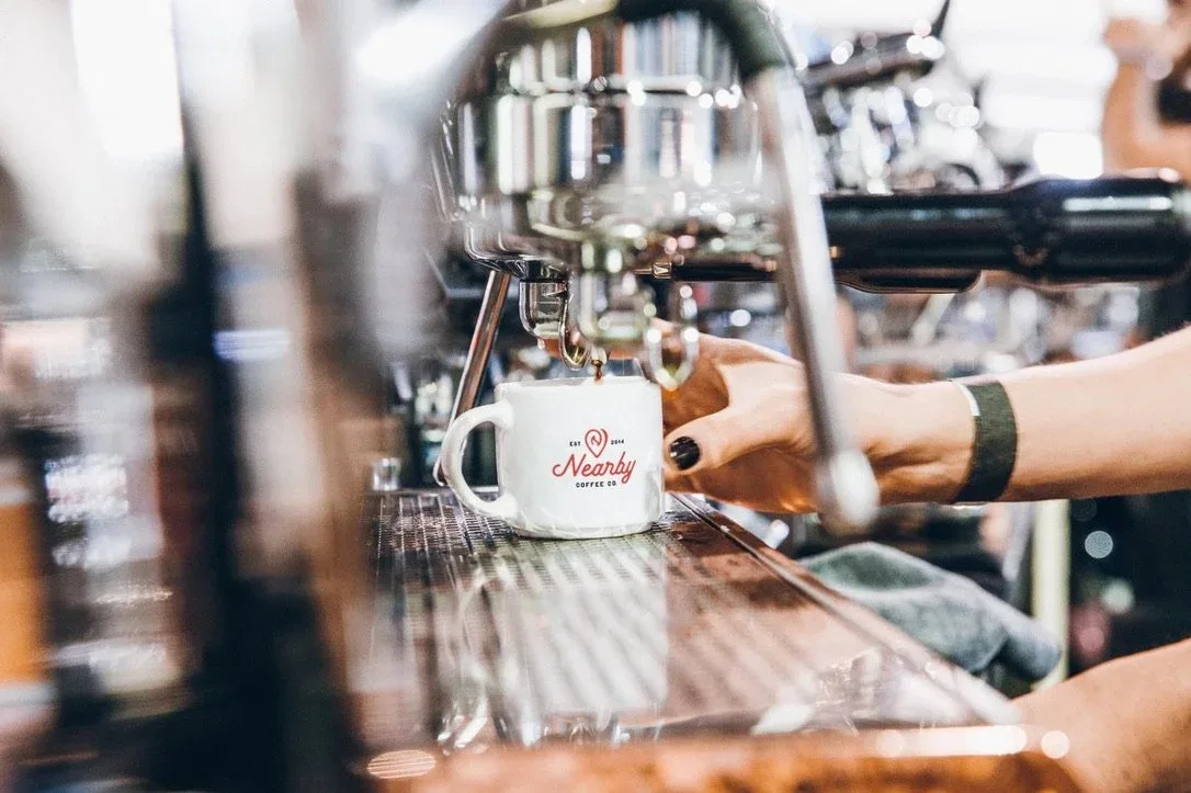barista pouring espresso into white nearby coffee co. cup at counter., nearby coffee co. catering services, austin