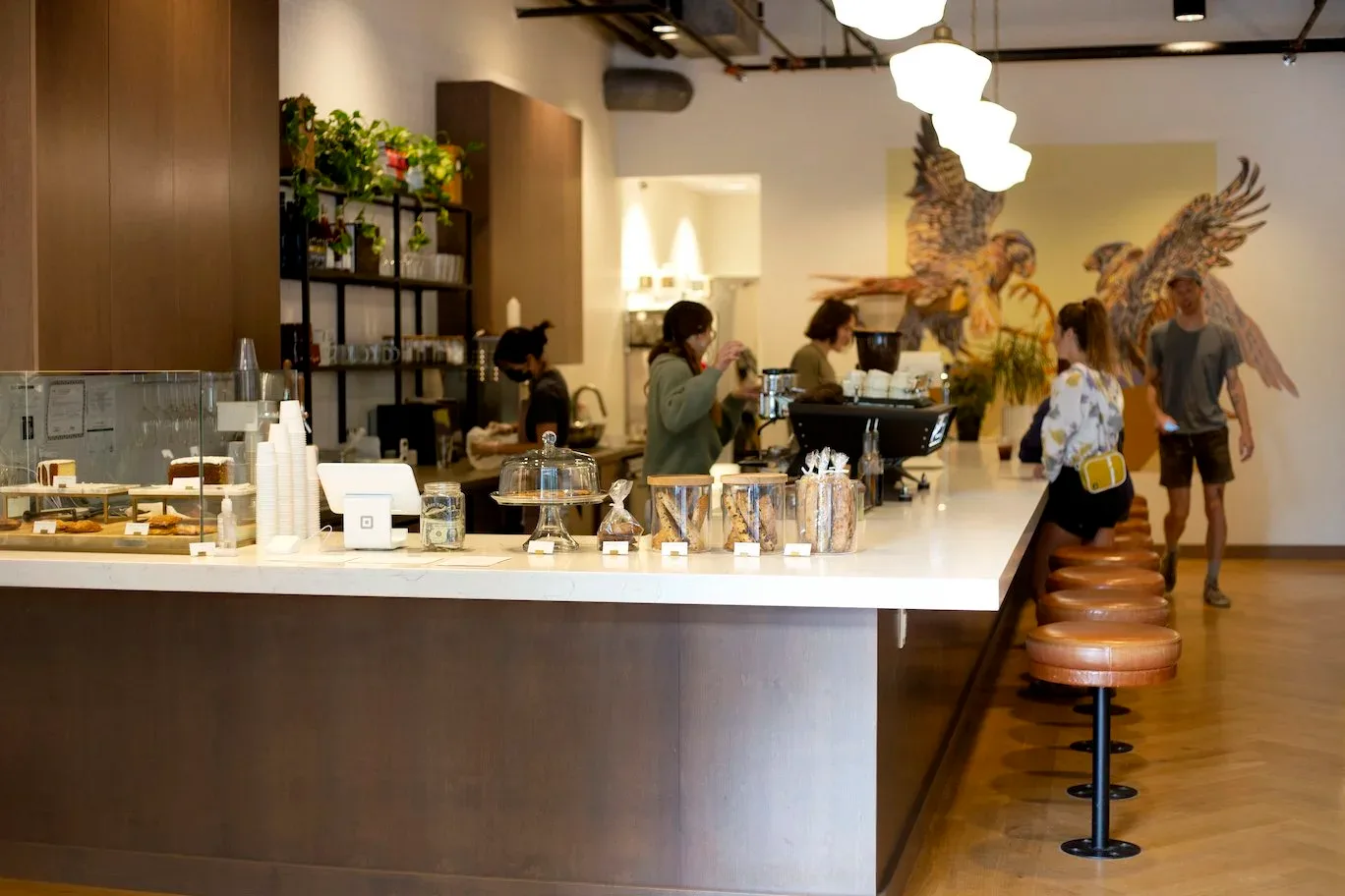 modern café interior with counter seating, customers, and decorative golden bird mural., neckar coffee, boise