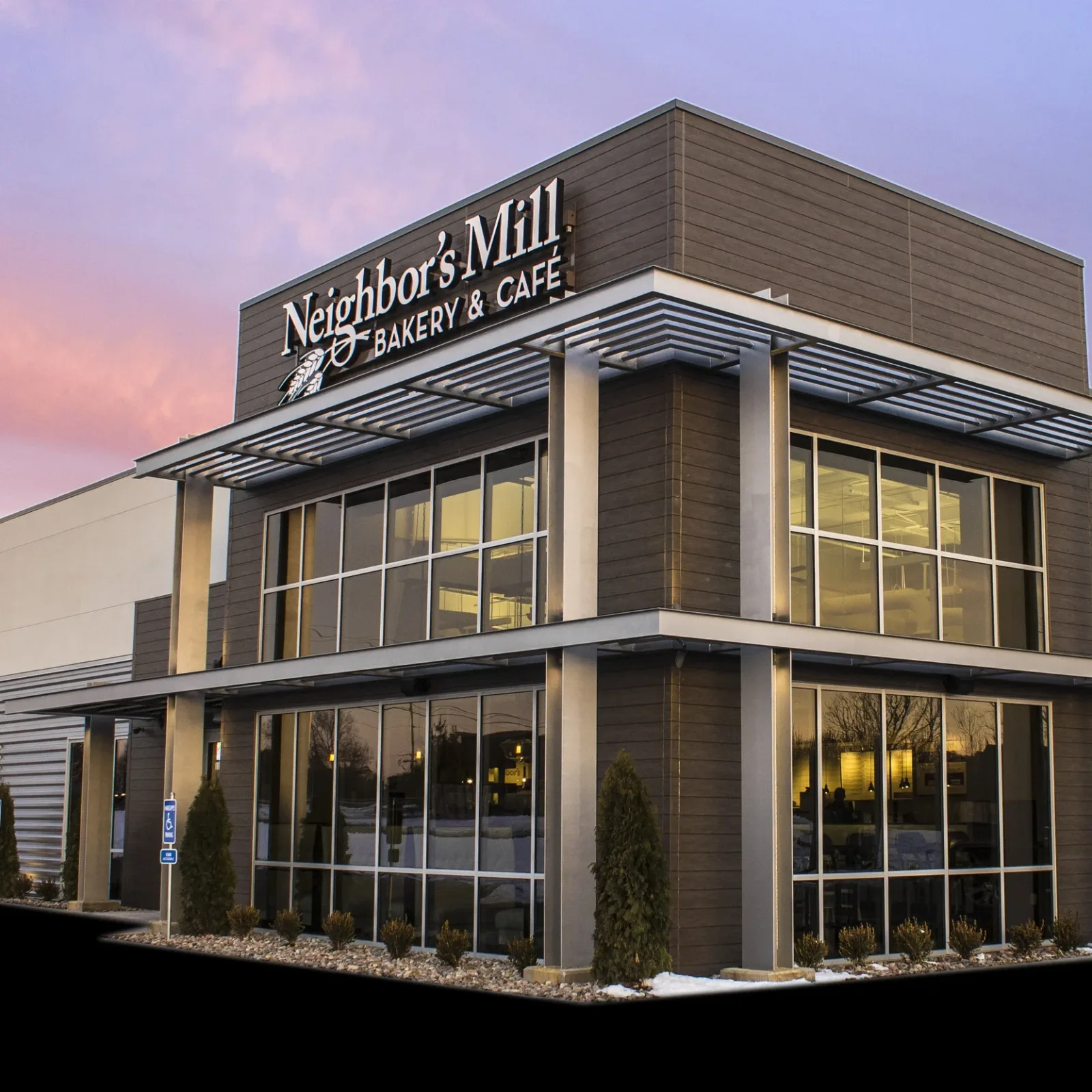 modern bakery and cafe building with illuminated signage at dusk., neighbor's mill bakery & cafe, harrison