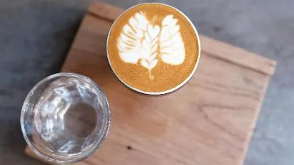 latte with leaf latte art, water glass on wooden board, overhead view., nida's coffee shop, chiang mai