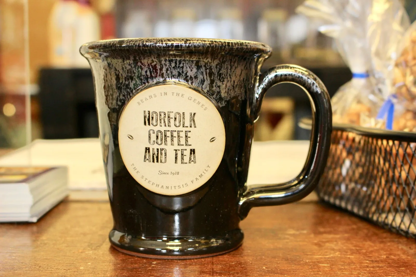 black ceramic mug labeled "norfolk coffee and tea" displayed on wooden surface., norfolk coffee & tea co, virginia