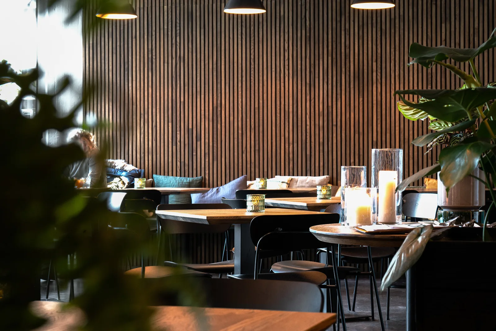 modern restaurant interior with wooden tables, pendant lights, and potted plants., nors food & drink, copenhagen