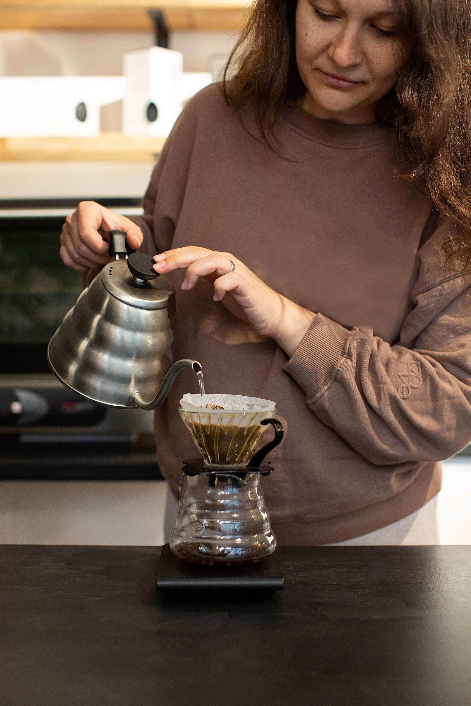 woman pouring hot water from gooseneck kettle into pour-over coffee dripper., north andes coffee, berlin