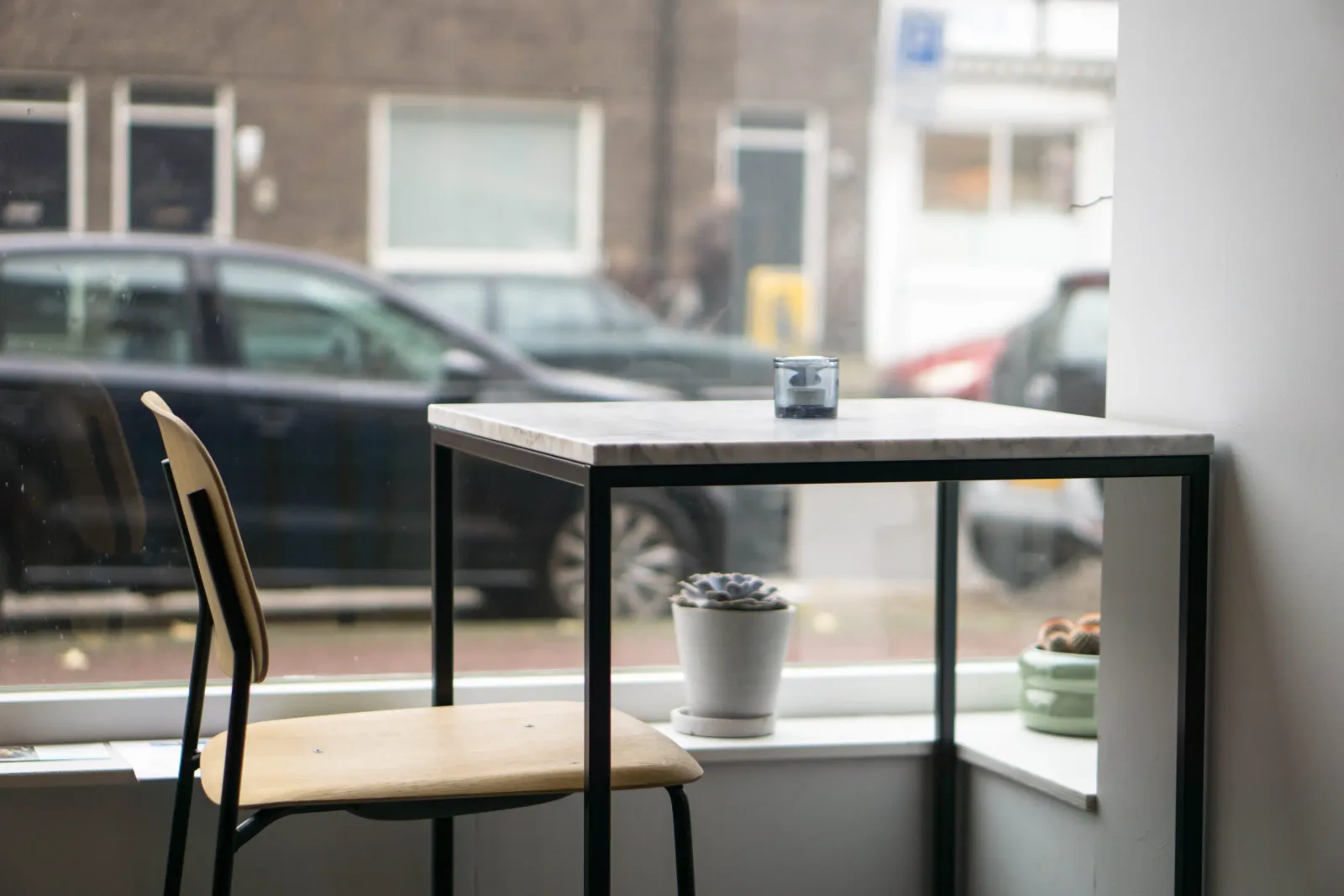 minimalist café interior with table, chair, and succulent plant by window overlooking street., ohøj coffee roasting, utrecht